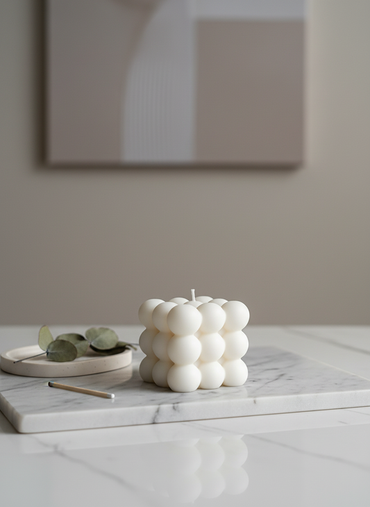 White bubble candle on a marble surface with a neutral background